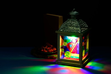 Photo of Decorative Arabic lantern and dates on table against dark background