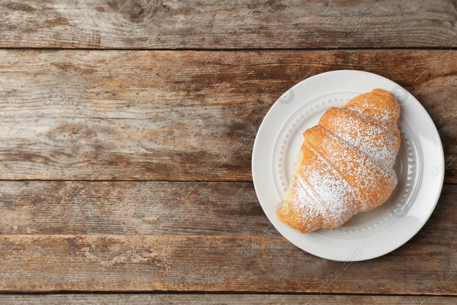 Photo of Plate with tasty croissant on wooden background, top view