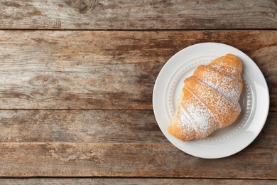 Photo of Plate with tasty croissant on wooden background, top view