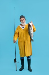 Fisherman with rod and catch on light blue background