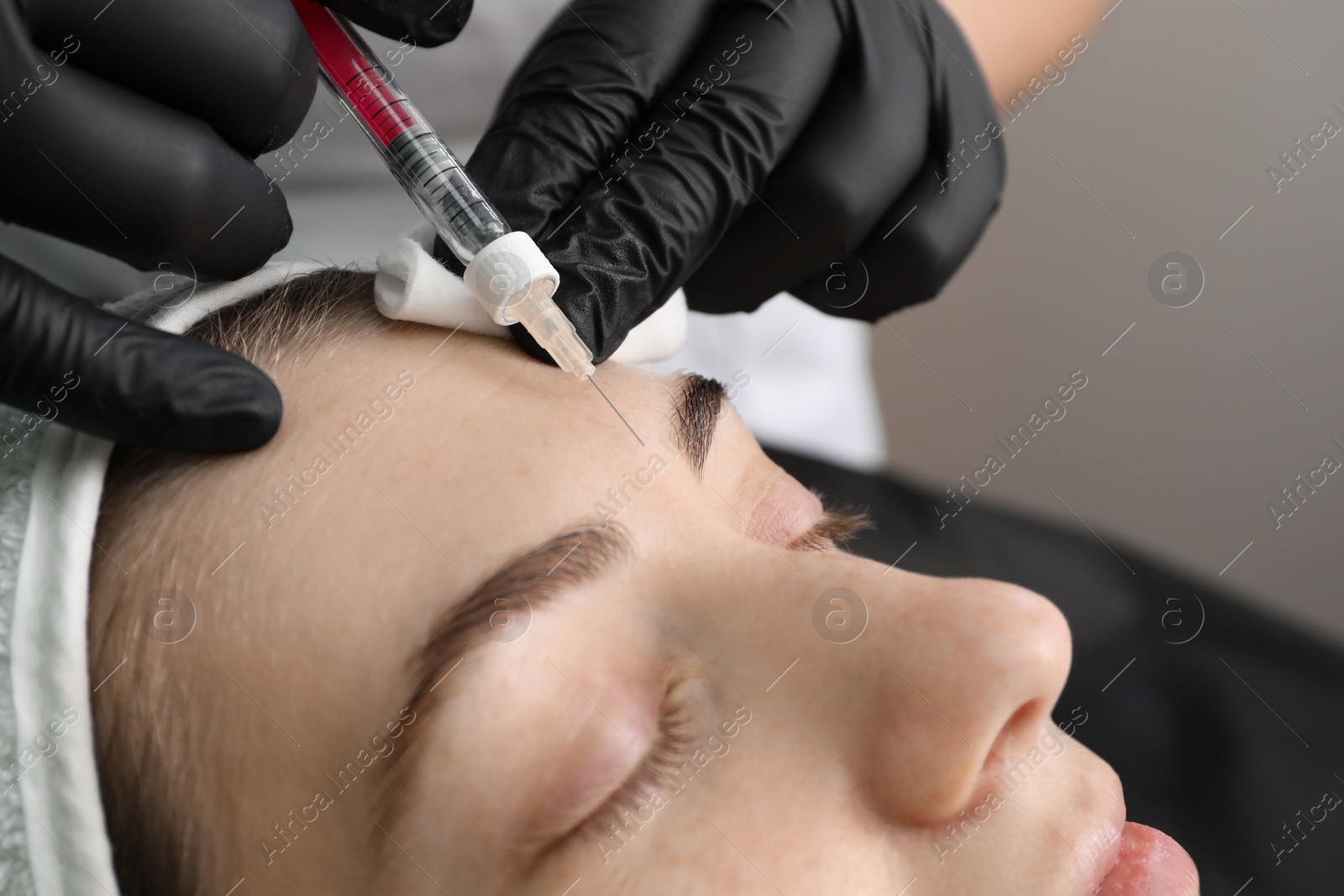 Photo of Cosmetologist giving facial injection to patient in clinic, closeup. Cosmetic surgery