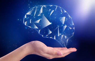 Image of Memory. Woman holding illustration of brain against dark blue background, closeup