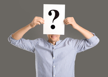 Photo of Man holding paper with question mark on grey background