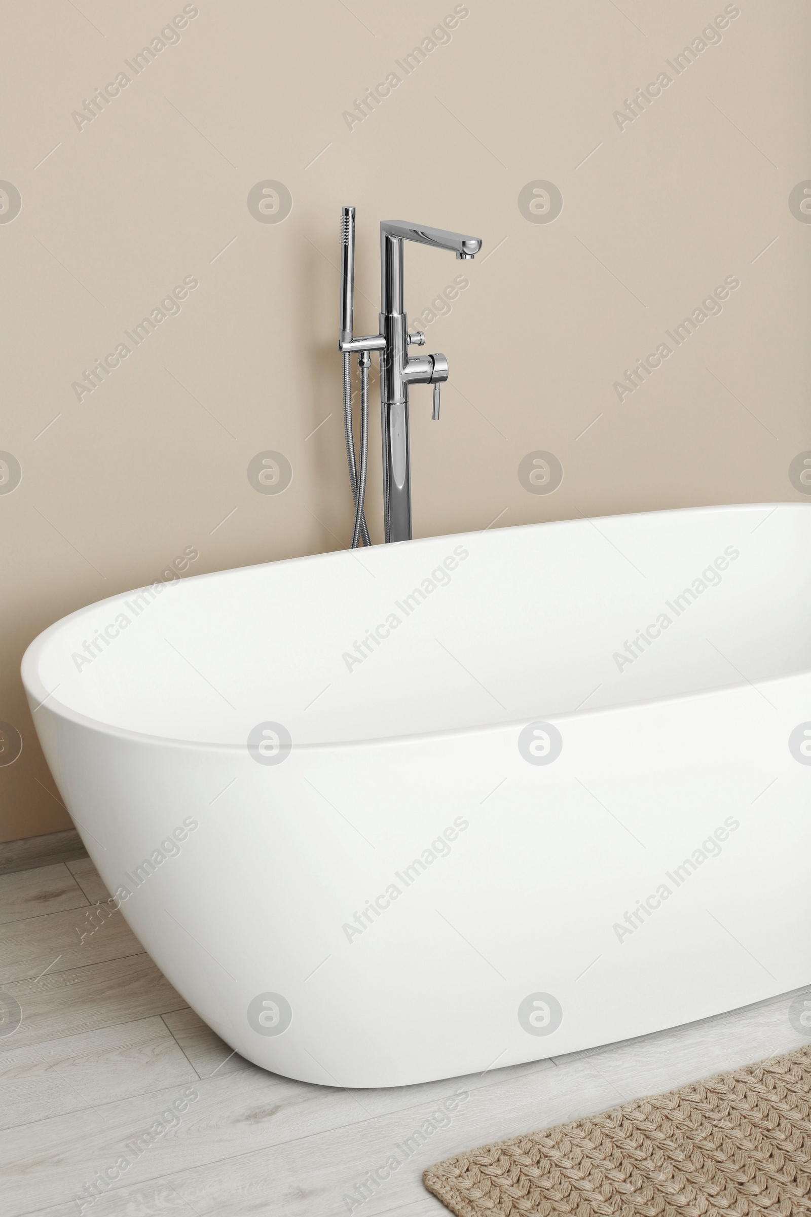 Photo of Beautiful white tub near beige wall in bathroom. Interior design