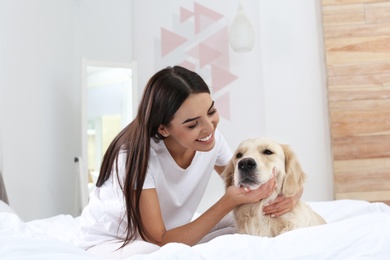 Photo of Young woman and her Golden Retriever dog on bed at home