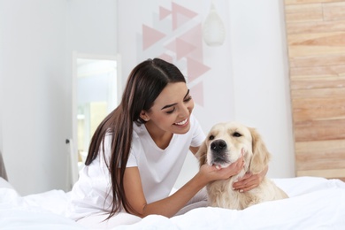 Young woman and her Golden Retriever dog on bed at home