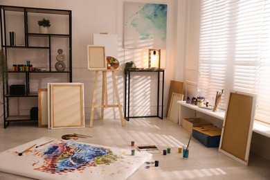 Photo of Wooden easel and abstract picture in art studio