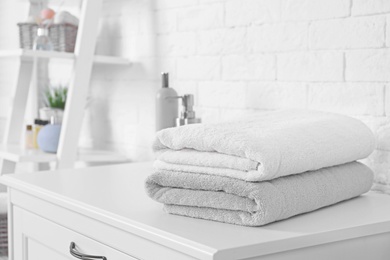 Photo of Stack of fresh towels on cabinet in bathroom. Space for text