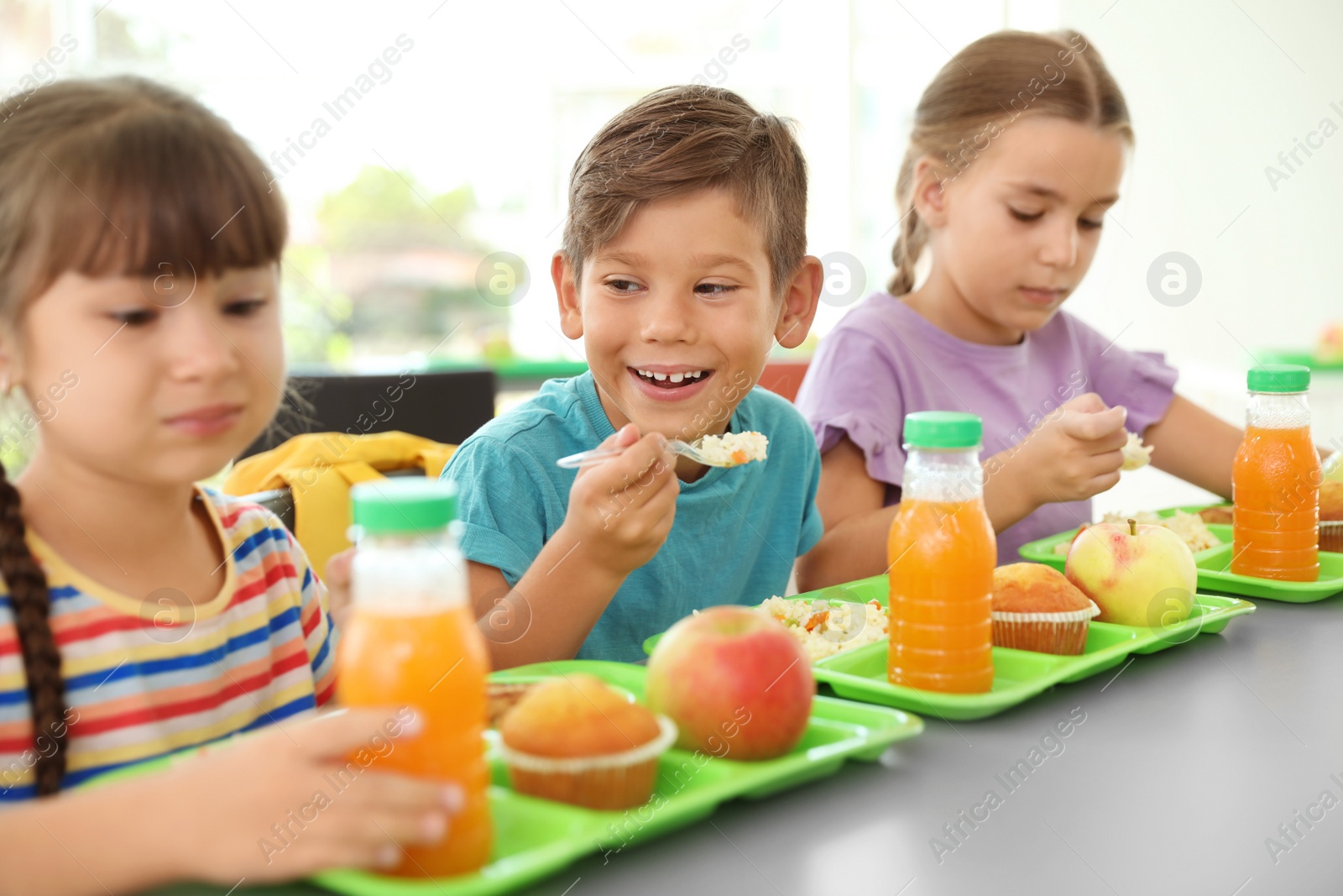 Photo of Children sitting at table and eating healthy food during break at school