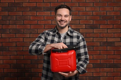 Man holding red canister against brick wall