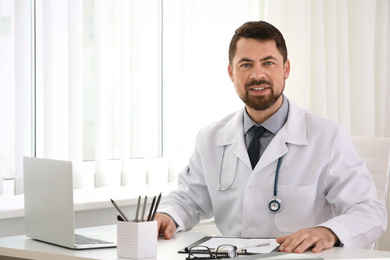 Portrait of male doctor in white coat at workplace