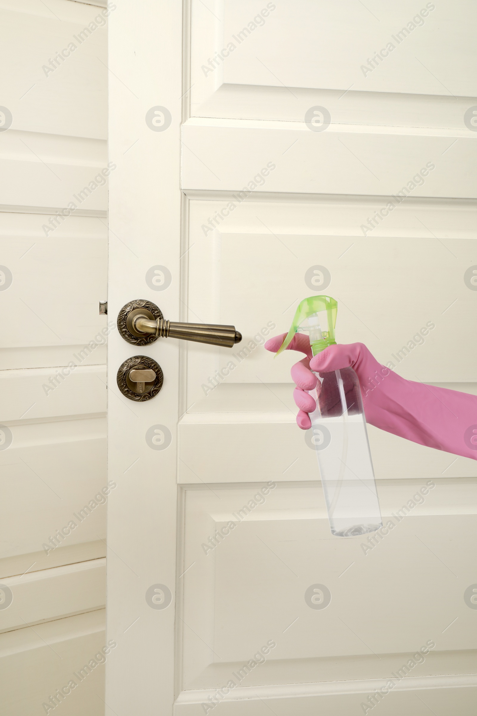 Image of Woman sanitizing door handle with antiseptic spray, closeup. Be safety during coronavirus outbreak