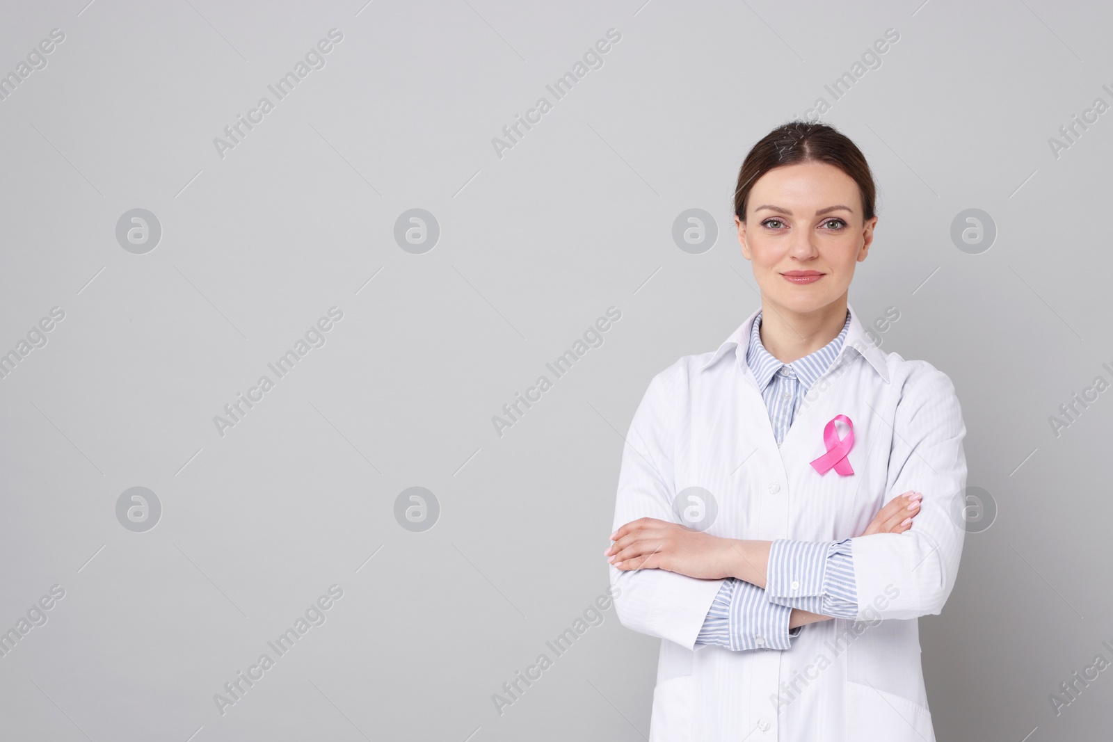 Photo of Mammologist with pink ribbon on grey background, space for text. Breast cancer awareness