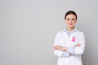 Mammologist with pink ribbon on grey background, space for text. Breast cancer awareness