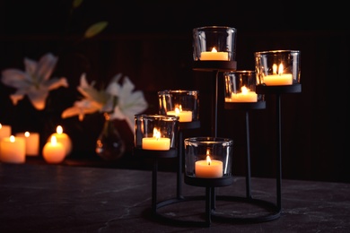 Photo of Holder with burning candles on table in darkness, space for text. Funeral symbol