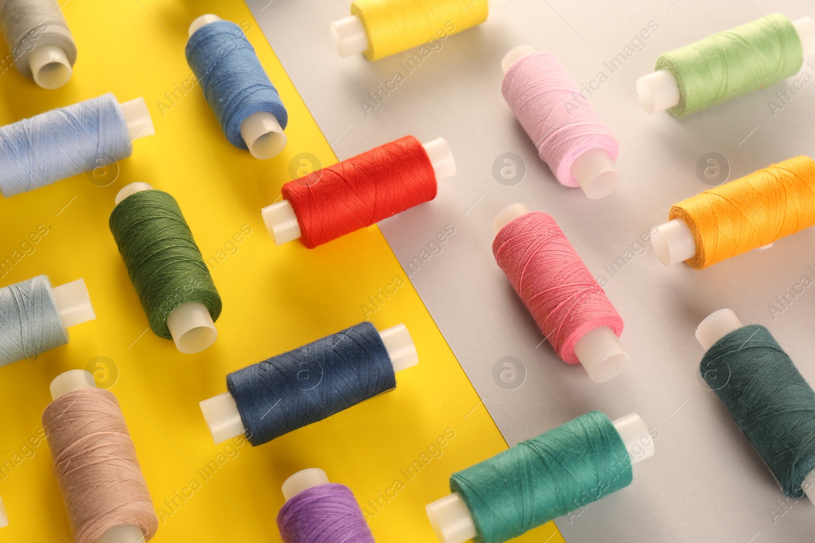 Photo of Set of different sewing threads on color background