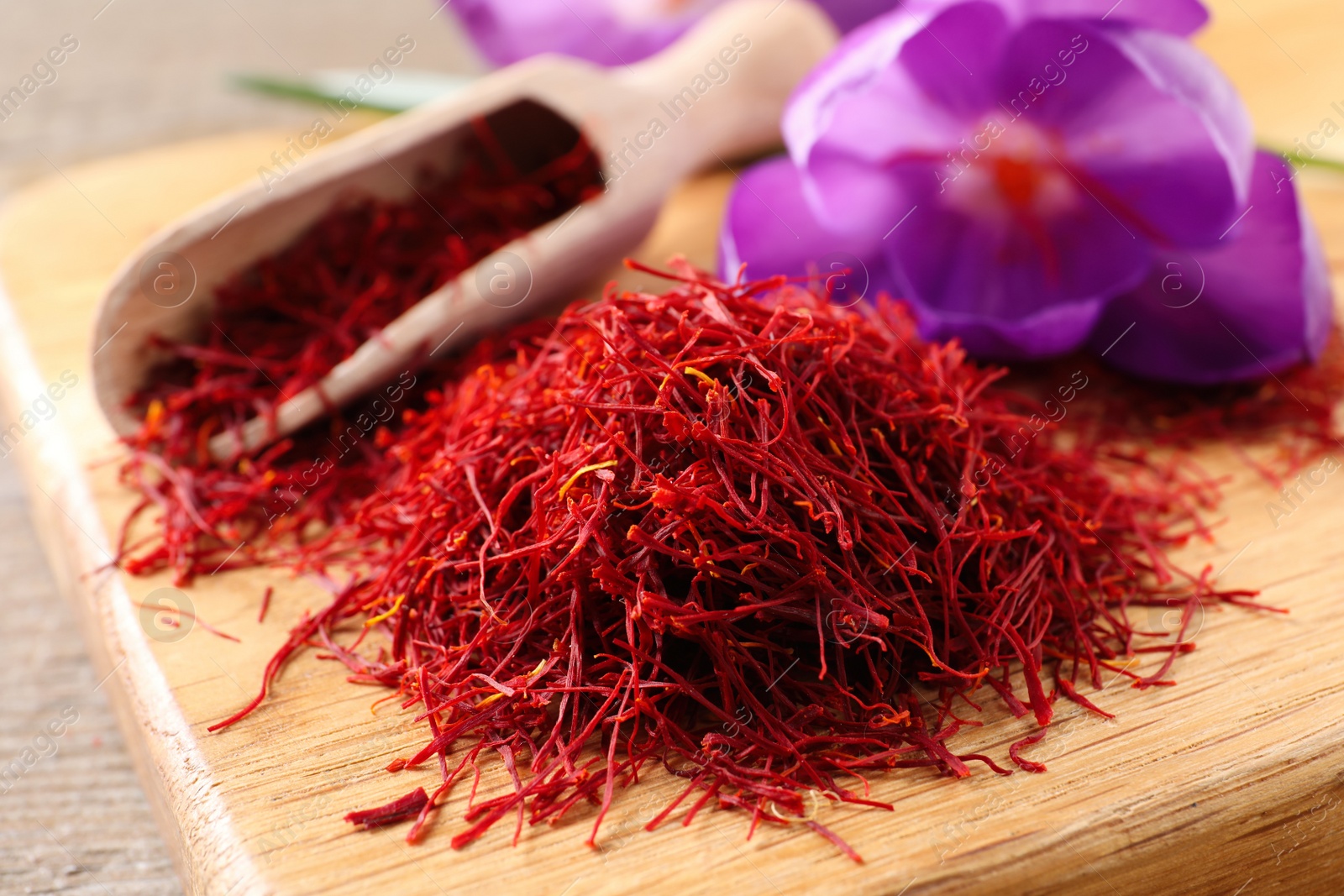 Photo of Dried saffron and crocus flowers on wooden board, closeup