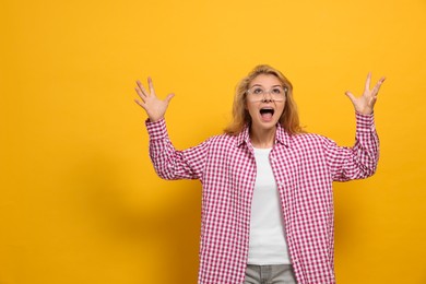 Aggressive young woman screaming with rage on yellow background. Space for text