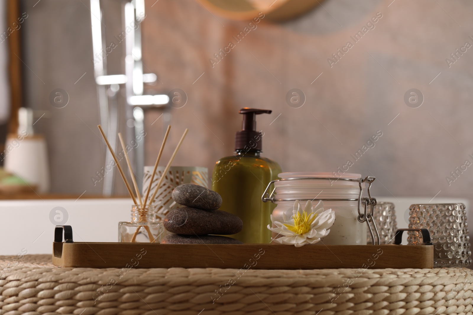 Photo of Different spa products and beautiful flower on wicker table in bathroom