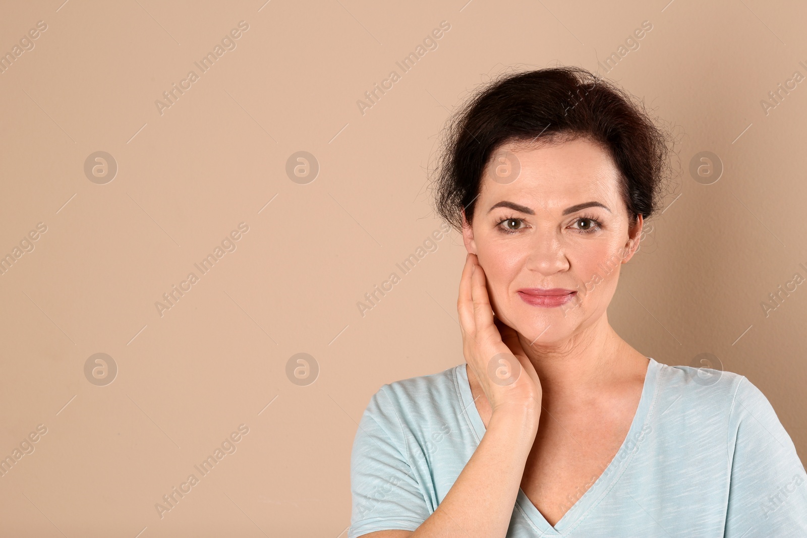 Photo of Portrait of charming mature woman with healthy beautiful face skin and natural makeup on beige background, space for text