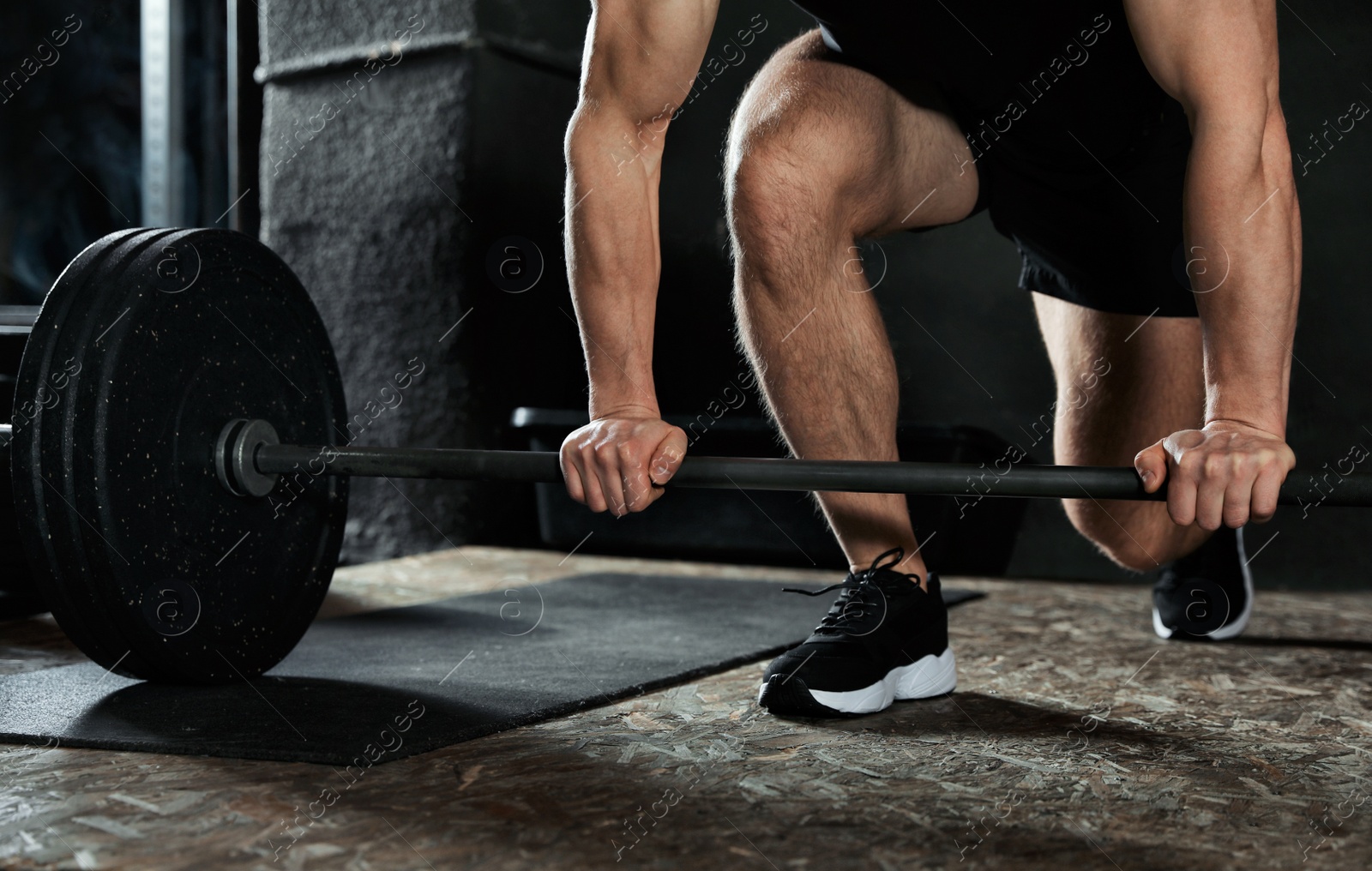 Photo of Man lifting barbell in modern gym, closeup