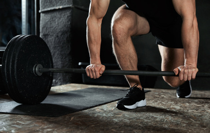 Photo of Man lifting barbell in modern gym, closeup