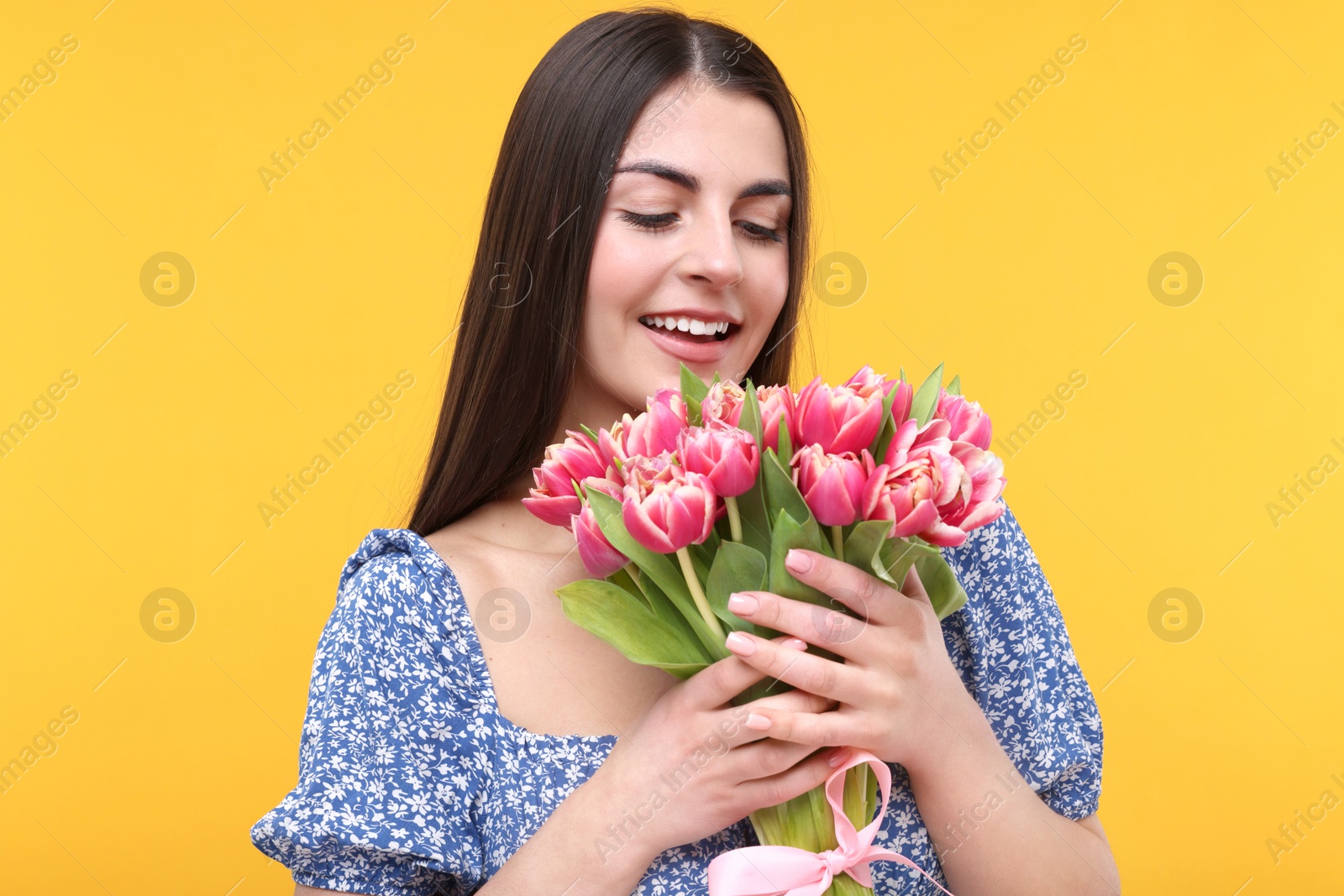 Photo of Happy young woman with beautiful bouquet on orange background