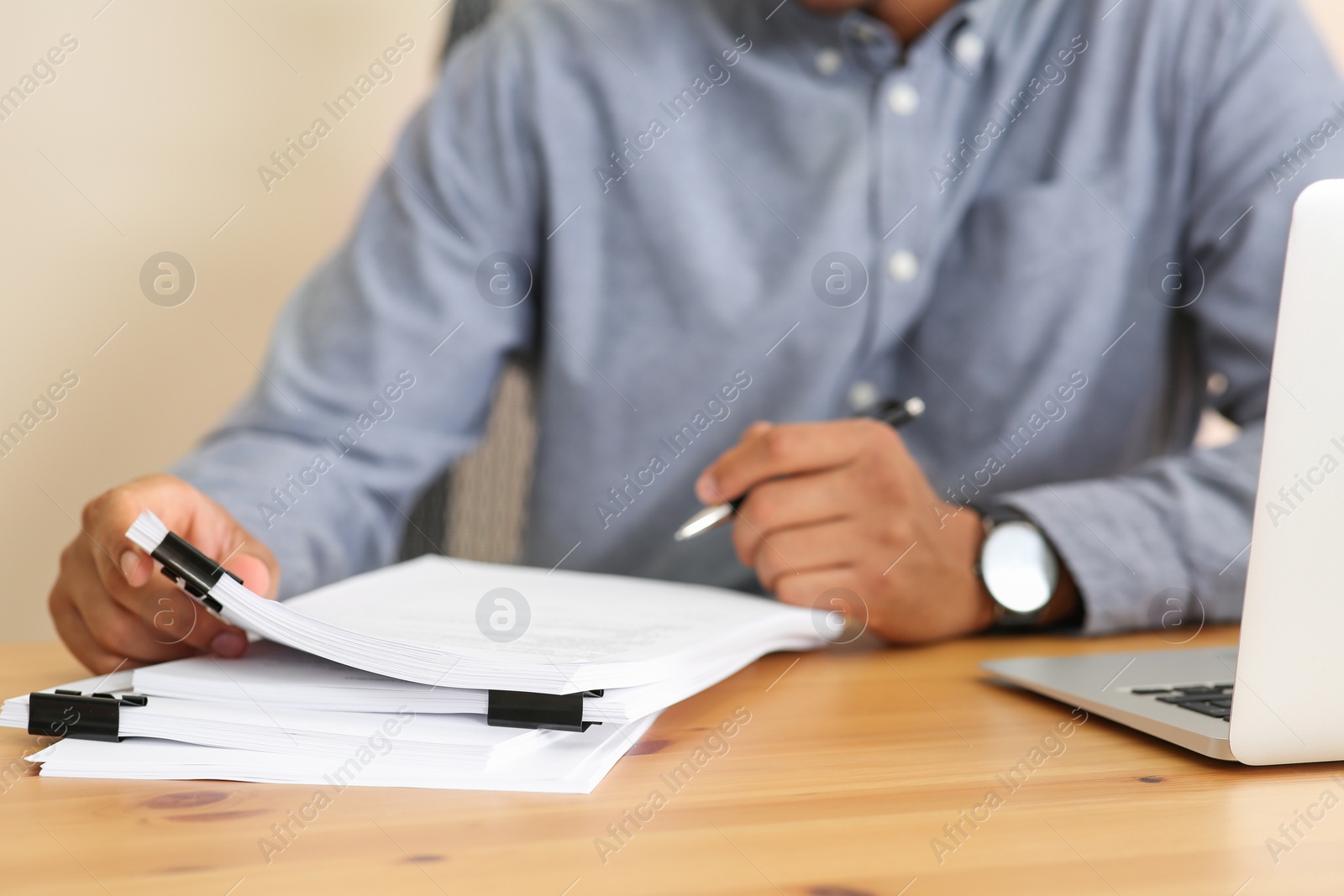 Photo of Man working with documents at wooden table in office, closeup