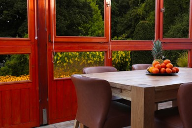 Wooden table with fruits and stylish chairs on terrace