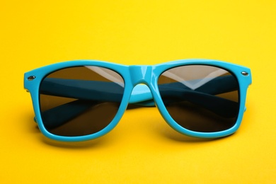 Photo of Stylish sunglasses on yellow background. Fashionable accessory