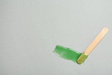 Photo of Spatula with wax on grey background, top view. Space for text