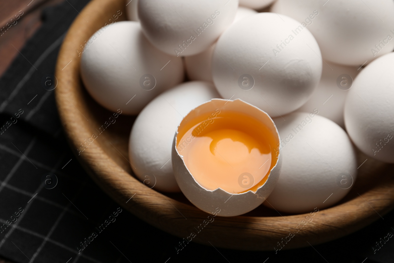 Photo of Many fresh raw chicken eggs in bowl on table, closeup