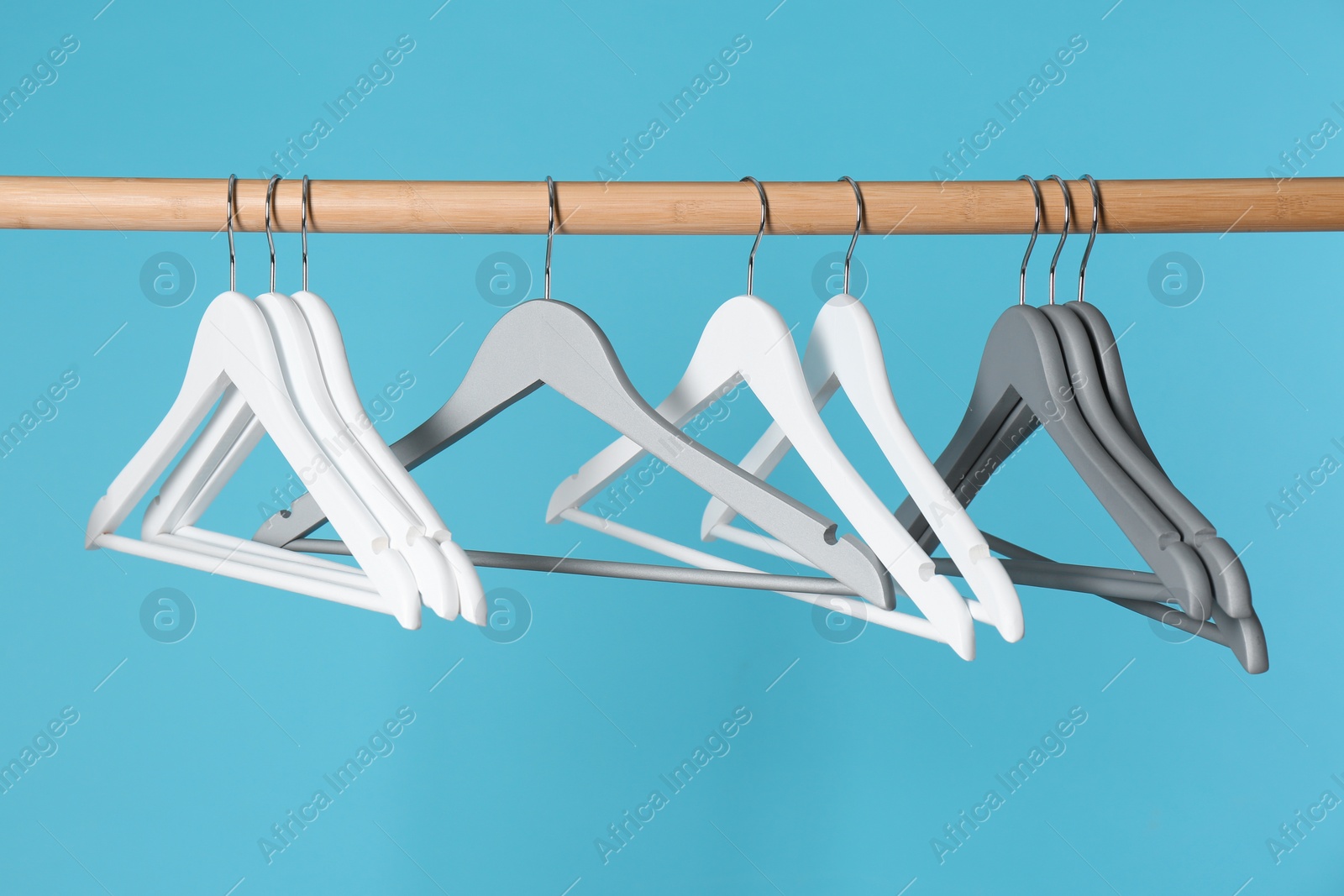 Photo of Wooden rack with clothes hangers on color background