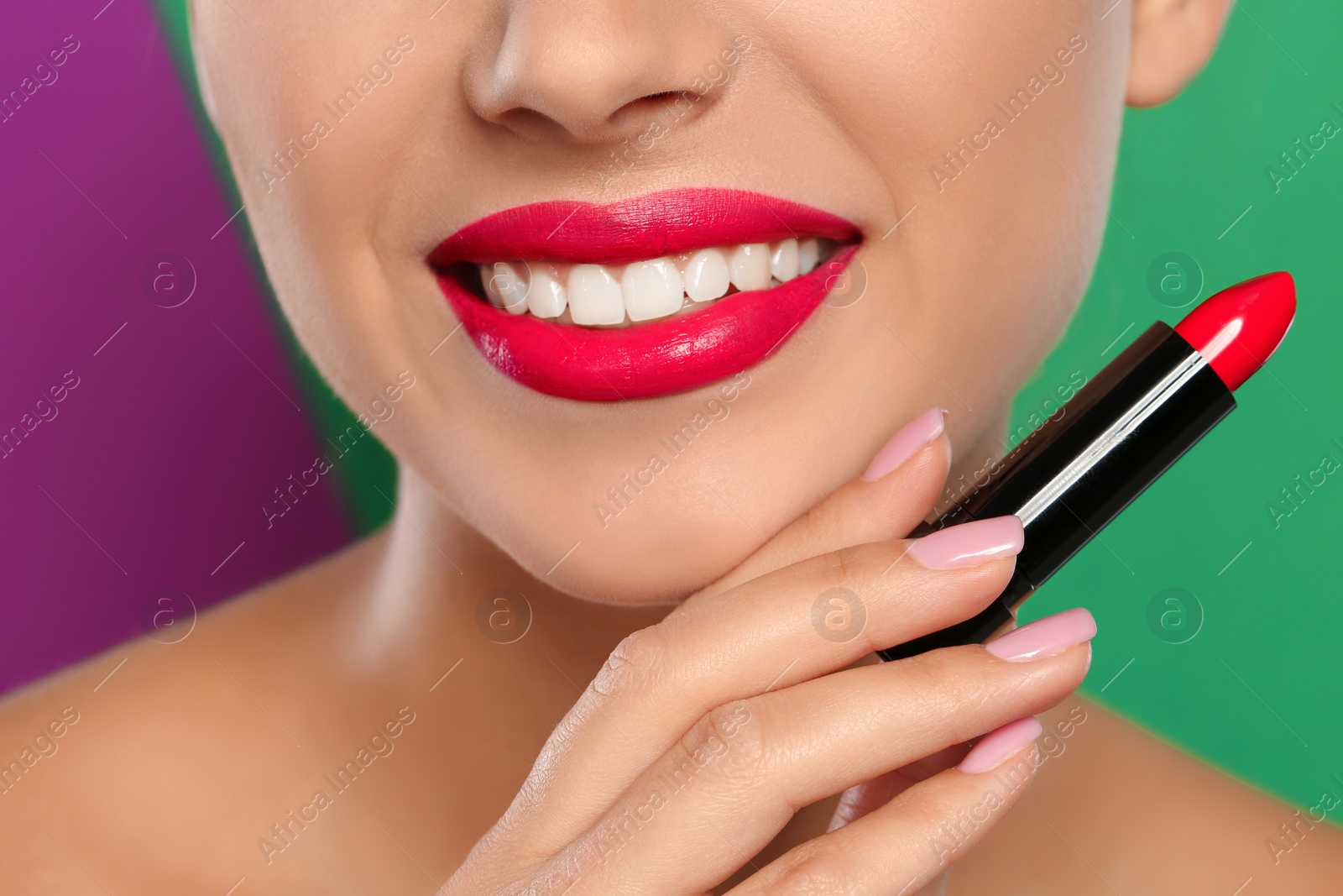 Photo of Young woman applying lipstick on color background, closeup