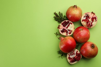 Flat lay composition with ripe pomegranates on green background. Space for text