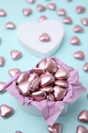 Photo of Box and delicious heart shaped candies on light blue background, closeup