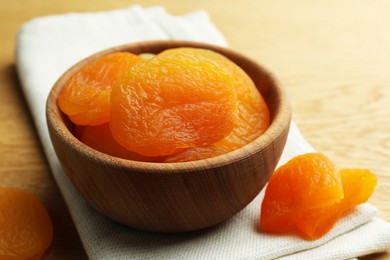 Photo of Bowl of tasty apricots on wooden table, closeup. Dried fruits