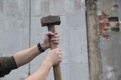 Man with sledgehammer outdoors, closeup. Space for text