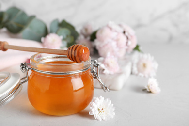 Jar of organic honey and chrysanthemum flower on light table. Space for text