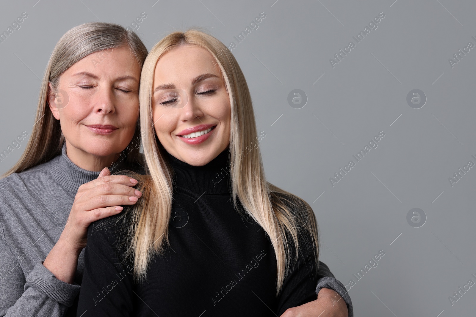 Photo of Family portrait of young woman and her mother on grey background. Space for text