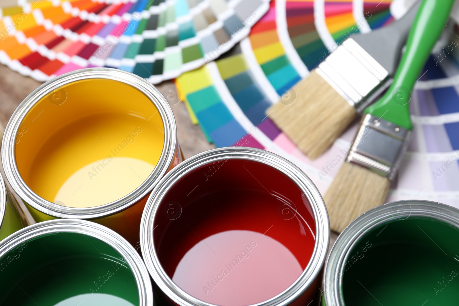 Photo of Paint cans, color palette samples and brushes on table. Closeup view