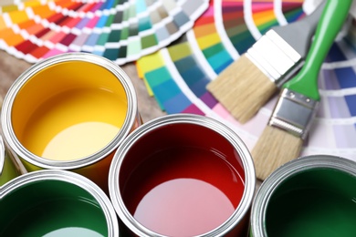 Photo of Paint cans, color palette samples and brushes on table. Closeup view