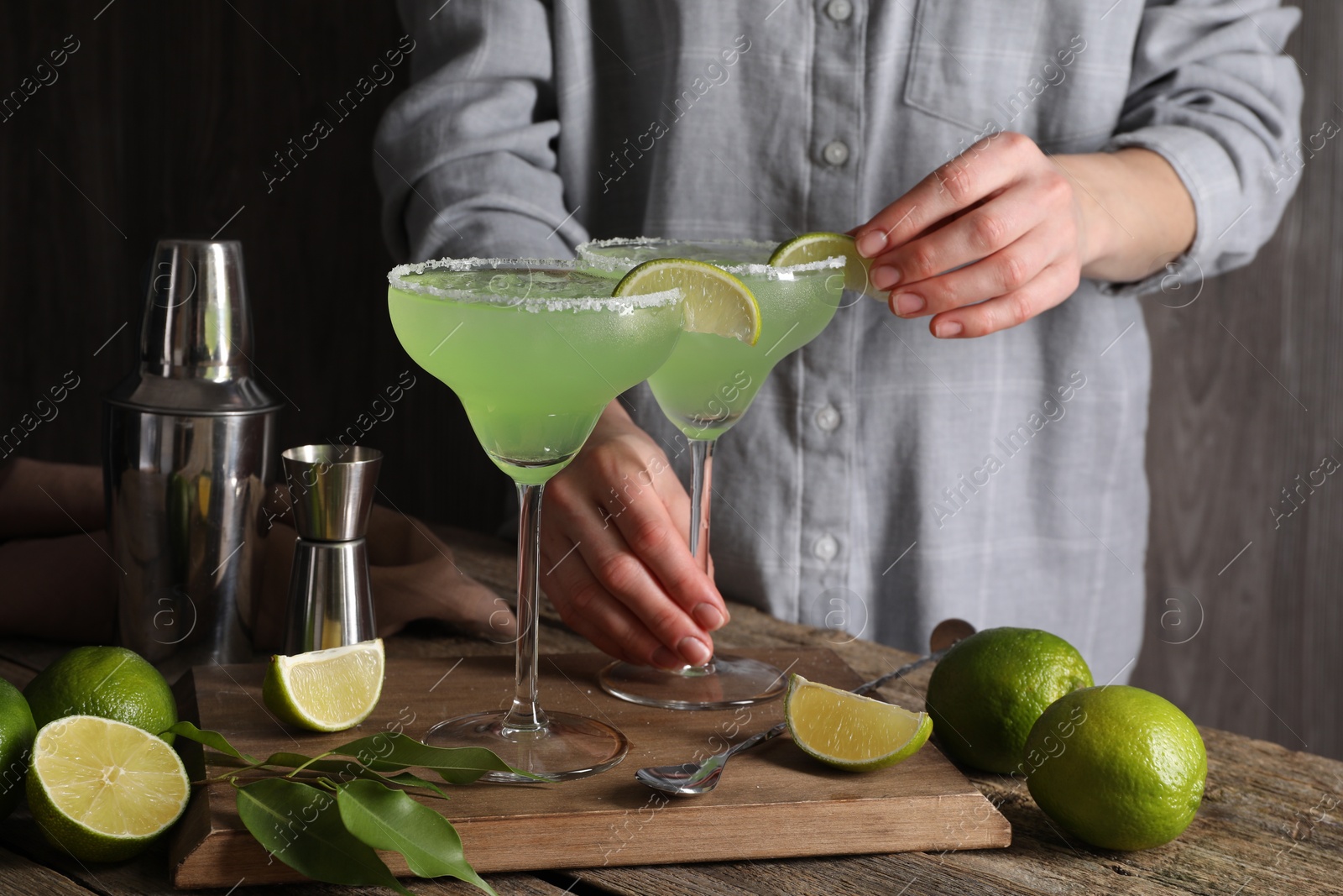 Photo of Woman making delicious Margarita cocktail at wooden table, closeup