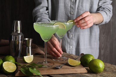 Photo of Woman making delicious Margarita cocktail at wooden table, closeup