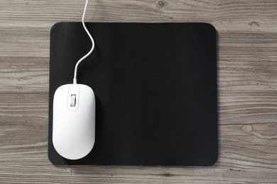 Wired mouse and mousepad on wooden table, top view