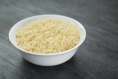Photo of Bowl of tasty couscous on grey table, closeup