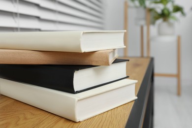 Stack of hardcover books on wooden table indoors, closeup