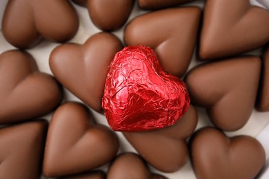 Tasty heart shaped chocolate candies on white background, flat lay. Valentine's day celebration