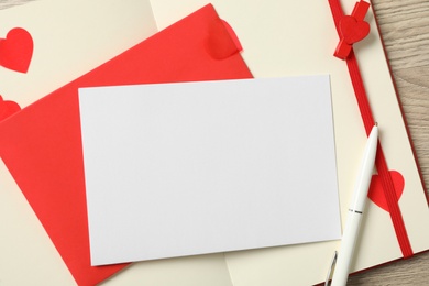 Photo of Blank card, envelope and notebook on wooden background, top view with space for text. Valentine's Day celebration