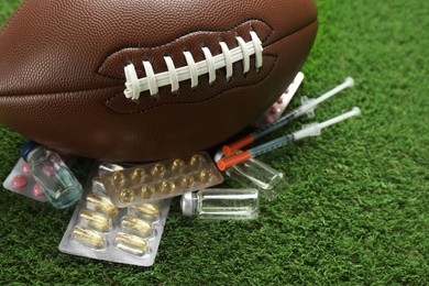 Photo of American football ball and different drugs on green grass, closeup. Doping concept